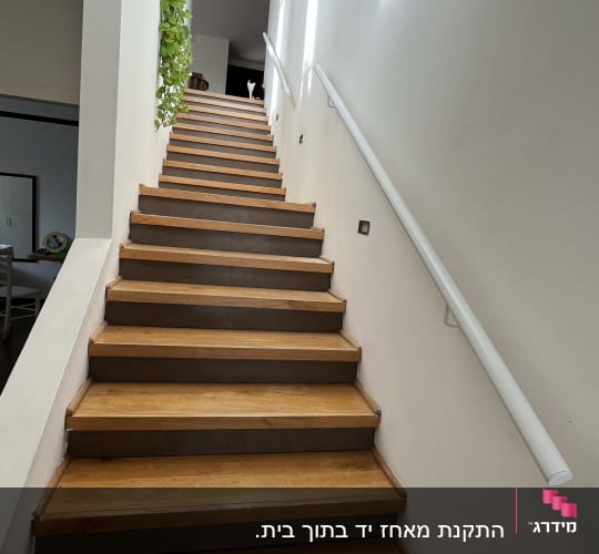 מעקה לבן לאורך גרם מדרגות עץ